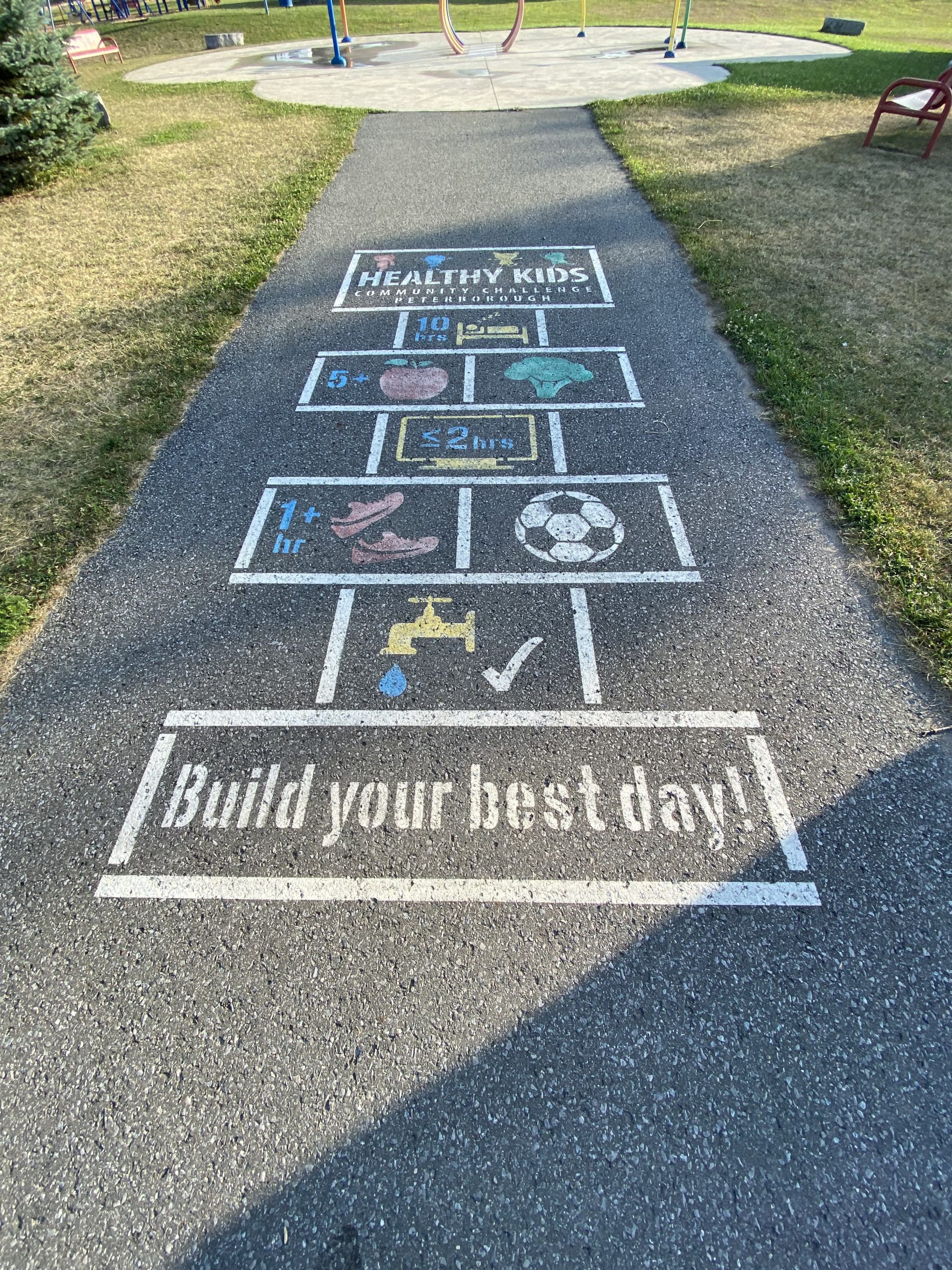 A picture of Healthy Kids being active at the park. The picture is on the cement at the entrance to the park in Norwood at the Norwood Community Centre to challenge kids to get Healthy