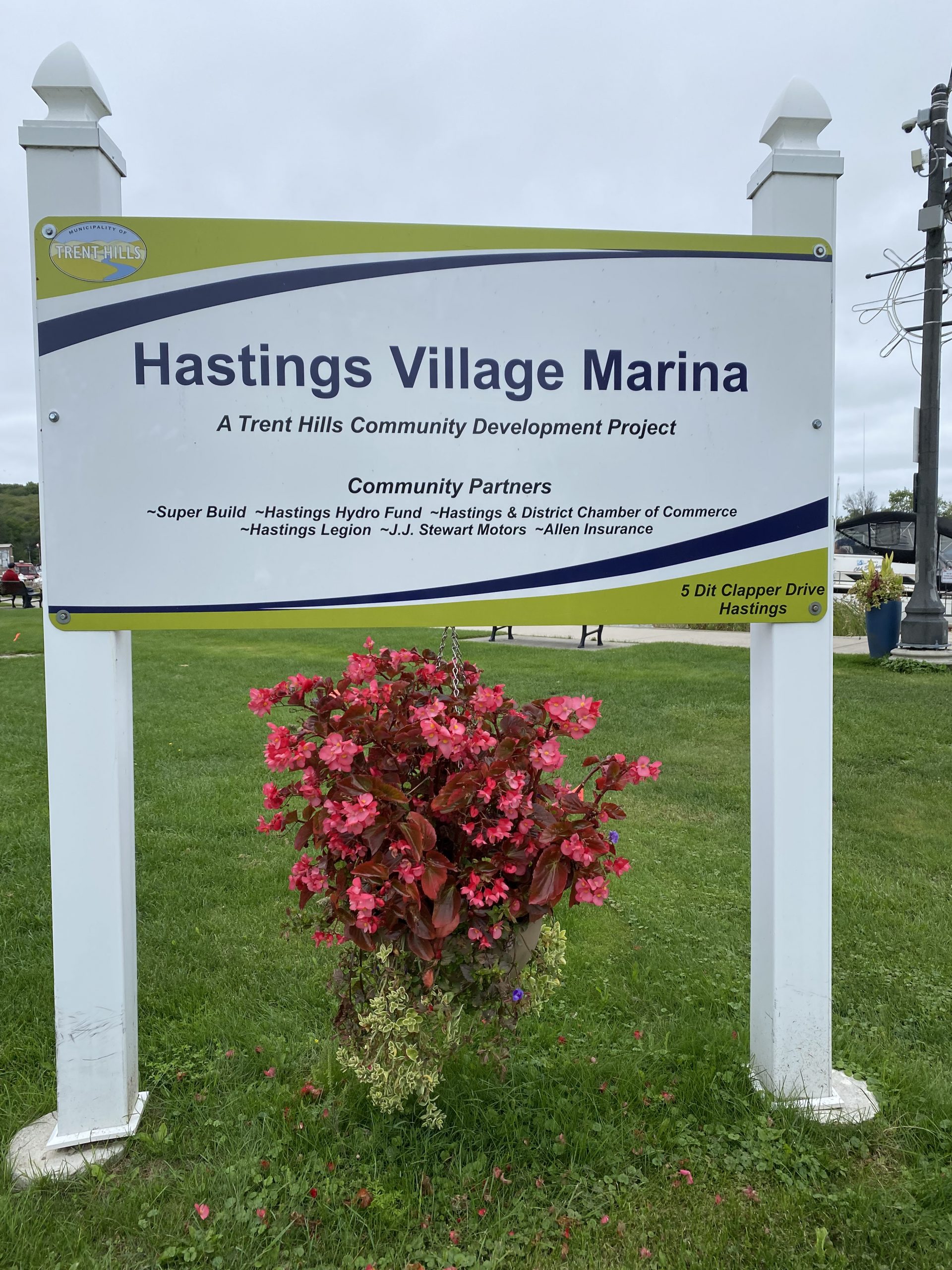Hastings Village Marina sign in the village of Hastings with a pot of red flowers below the sign
